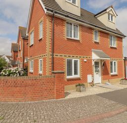 A brick house with multiple windows and a white door with small planters outside at 12 Clos Yr Wylan in Barry