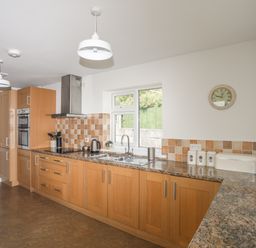 A kitchen with wooden cabinets countertop appliances and a window at Glan Awel in Nefyn