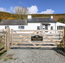 A wooden gate with a sign reading Pennant Cottage Private Estate and a white cottage behind it at Pennant Cottage in Llithfaen