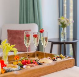 A wooden tray with food and champagne glasses at Carines Barns - Pen, Cubert
