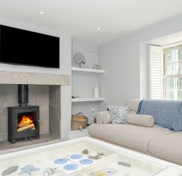 A living room with a fireplace a television a sofa and a coffee table at Cob Cottage near Rock