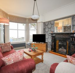 A living room with two red sofas a wooden coffee table and a fireplace at Llwyn Onn in Criccieth