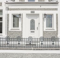 A front entrance door with glass panels flanked by two windows and black metal fence at Llwyn Onn in Criccieth