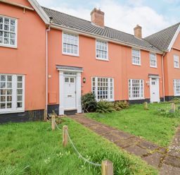 A row of orange townhouses with white doors and windows and green lawns in front at 23 Church Farm Lane in Halesworth