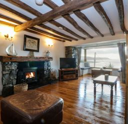 A living room with a fireplace and television at Ty'n-Y-Ffynnon Cottage Barmouth