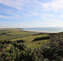 A coastal landscape with fields houses and a beach by the sea at Ty Rhosyn in Penycwm near Solva