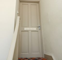 A closed beige door with a sign labeled Upper Oakwood at the top of a carpeted staircase in a hallway at Upper Oakwood in Alnwick