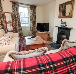 A sitting room with two sofas a wooden coffee table a television on a wooden chest and a fireplace at Upper Oakwood in Alnwick