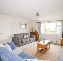 A living room with two sofas a wooden coffee table wooden furniture and a television at 7 Maes Awel in Abersoch