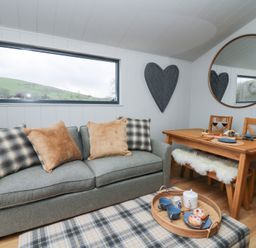 A living room with a sofa and dining table at Fawn’s Rest in Nantmel near Rhayader