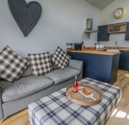 A living room with a sofa and kitchen area at Doe Lodge Nantmel near Rhayader