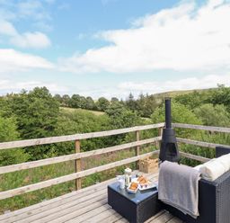 An outdoor deck with furniture and a chiminea at Cuckoo at Wild Valley Huts Llanrhaeadr-Ym-Mochnant