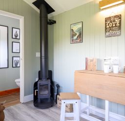 A room with a wood stove and a table with coffee cups at Cuckoo at Wild Valley Huts Llanrhaeadr-Ym-Mochnant