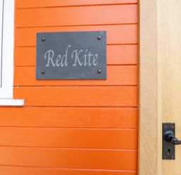A sign labeled Red Kite on an orange wall at Red Kite at Wild Valley Huts in Llanrhaeadr-Ym-Mochnant