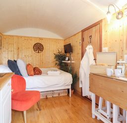 A bedroom with a bed and a table at Red Kite at Wild Valley Huts Llanrhaeadr-Ym-Mochnant