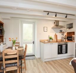 A kitchen with a dining table chairs stove and refrigerator at Bwthyn Lili (Lily Cottage) in Cemaes Bay