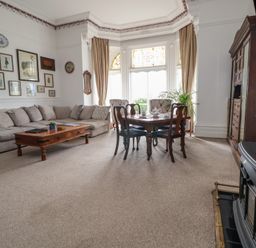 A living room with a beige sofa coffee table dining table chairs cabinet and a fireplace at Ismay Dining Room Suite - Titanic Interest Waterloo Merseyside