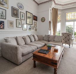 A sitting room with a large corner sofa a wooden coffee table and decorative wall art at Ismay Dining Room Suite - Titanic Interest in Waterloo Merseyside