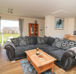 A living room with a large sectional sofa coffee table bookshelves and dining table at Brynteg Cottage in Tegryn