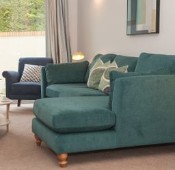 A sitting room with a teal sofa and armchair with cushions and a coffee table at Brooklands in Uplyme