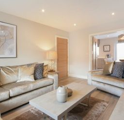 A living room with beige sofas a coffee table and a lamp at Sans Souci in Seahouses