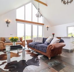 A living room with two sofas glass coffee table and large windows at Polly's Annexe in Levington