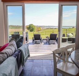 A living room with a view of the patio and landscape at Polly's Annexe Levington