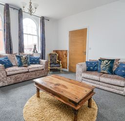A living room with two sofas a wooden coffee table and a blue armchair at The Old Station House Withernsea