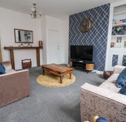 A living room with two sofas a wooden coffee table a television on a stand and a wall clock at The Old Station House in Withernsea