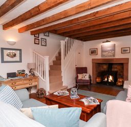 A living room with wooden beams a fireplace a wooden coffee table and a staircase at Seahares in Seahouses
