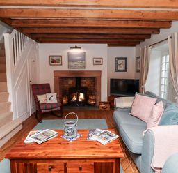A living room with a wooden coffee table sofas a fireplace and a staircase at Seahares in Seahouses