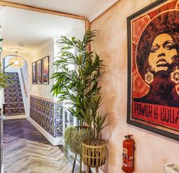 A hallway with patterned stairs and wall decor including a framed artwork and plants at Clematis House in St Columb Major