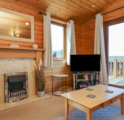 A living room with a fireplace a mirror a small table a television on a stand and a wooden coffee table at Seascape Retreat in Ilfracombe