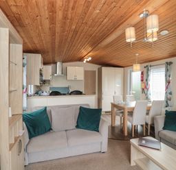 An open-plan living room and kitchen with sofas dining table and wooden ceiling at Beech in Swanage