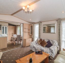 A living room with sofas a wooden coffee table and a kitchen and dining area visible through an open doorway at Birch in Swanage