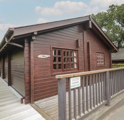 A wooden cabin named Pine with a wheelchair accessible ramp and caution sign at Pine in Swanage