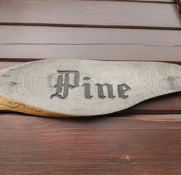A wooden sign with the word Pine mounted on a wooden wall at Pine in Swanage