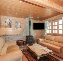 A living room with two beige sofas a stone fireplace a wooden ceiling and a coffee table at Pine in Swanage