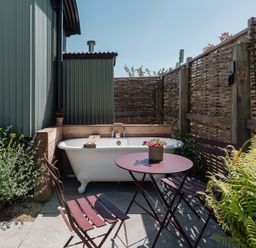 An outdoor area with a bathtub and seating at Hurdlemakers Hut in Piddletrenthide