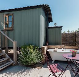 An outdoor area with a bathtub and seating at Hurdlemakers Hut in Piddletrenthide