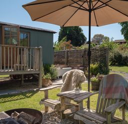 A garden area with chairs and an umbrella at Hurdlemakers Hut in Piddletrenthide