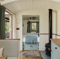 A living room with a bed and stove at Hurdlemakers Hut in Piddletrenthide