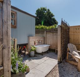 An outdoor area with a bath tub and seating at Spindleberry Hut in Piddletrenthide