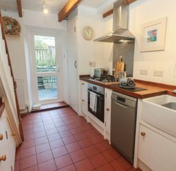 A kitchen with appliances and a door at Bodillys Cottage in Newlyn
