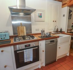 A kitchen with stove, sink, and dishwasher at Bodillys Cottage in Newlyn