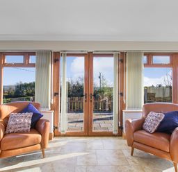 A room with two brown armchairs and glass doors leading to an outdoor area at Rose Cottage in Muff County Donegal