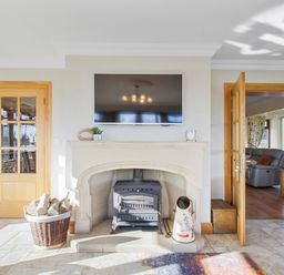 A fireplace with a wood stove and a basket of firewood in a living space at Rose Cottage in Muff County Donegal