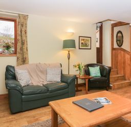 A sitting room with a green sofa and chair near a staircase at Winder Barn in Askham Cumbria