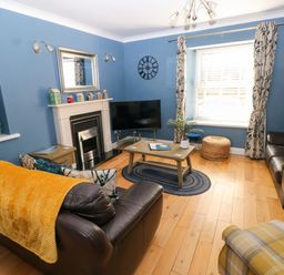 A living room with blue walls two leather sofas a wooden coffee table and a fireplace at Stones Throw in Tenby