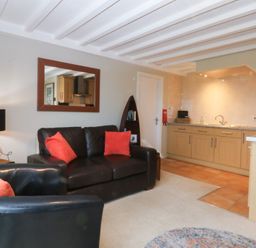 A living room with a sofa and kitchen area at Oak Cottage in Dinas Dinlle near Caernarfon